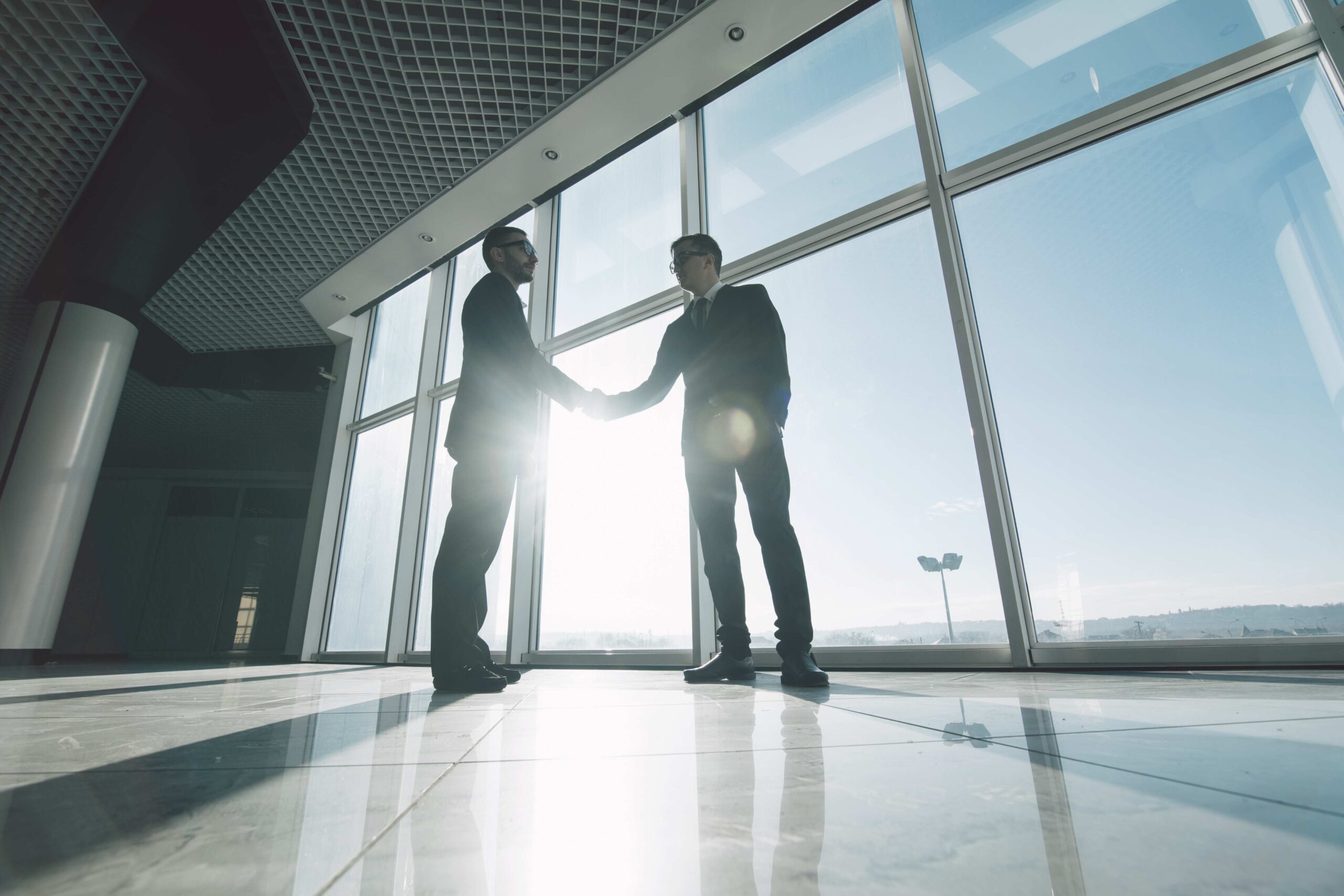 Two attorneys shaking hands in a law firm skyrise lobby